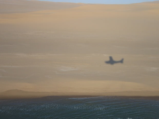 Flugzeug vor der Kulisse von Dünen und Atlantik